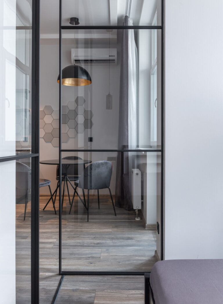 Modern living room interior with lamp and glass partition against table with chairs in house